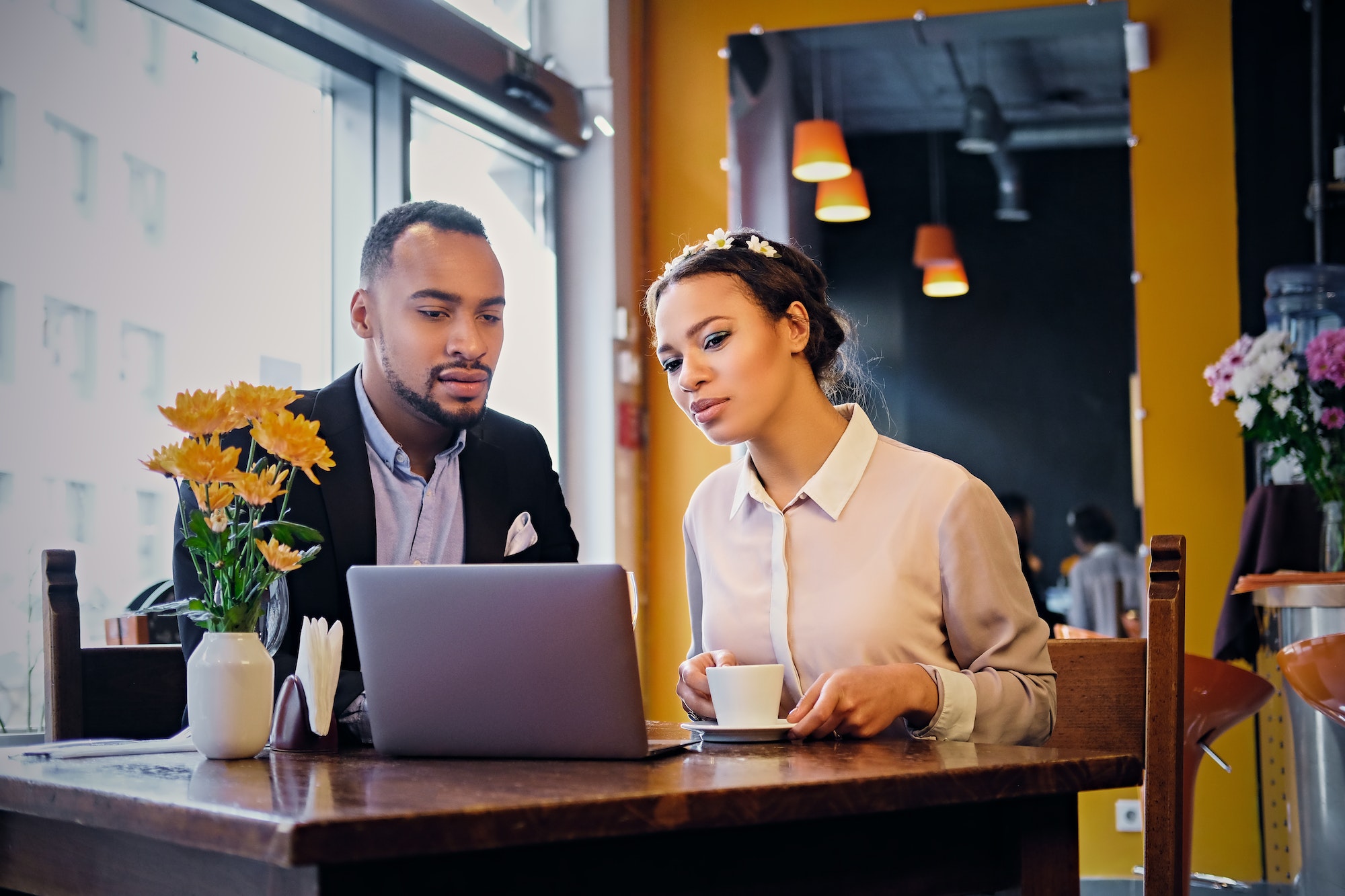 Black couple using laptop in a cafe.