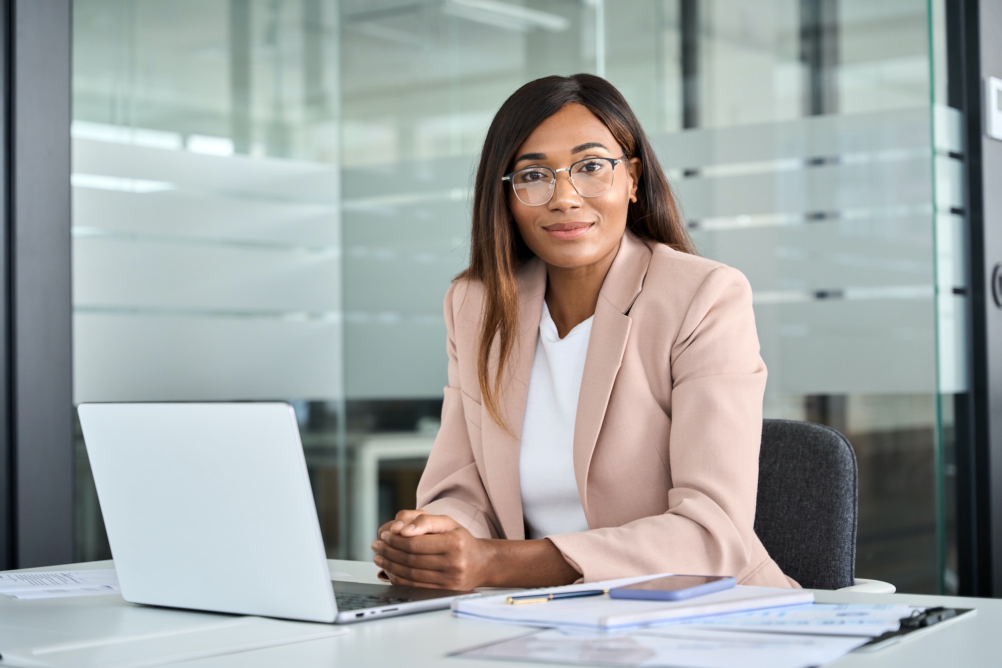 Professional African American business woman sitting at office desk, portrait.